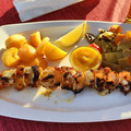 Grilled seafood kebab with roasted potatoes and vegetables on white plate at outdoor restaurant